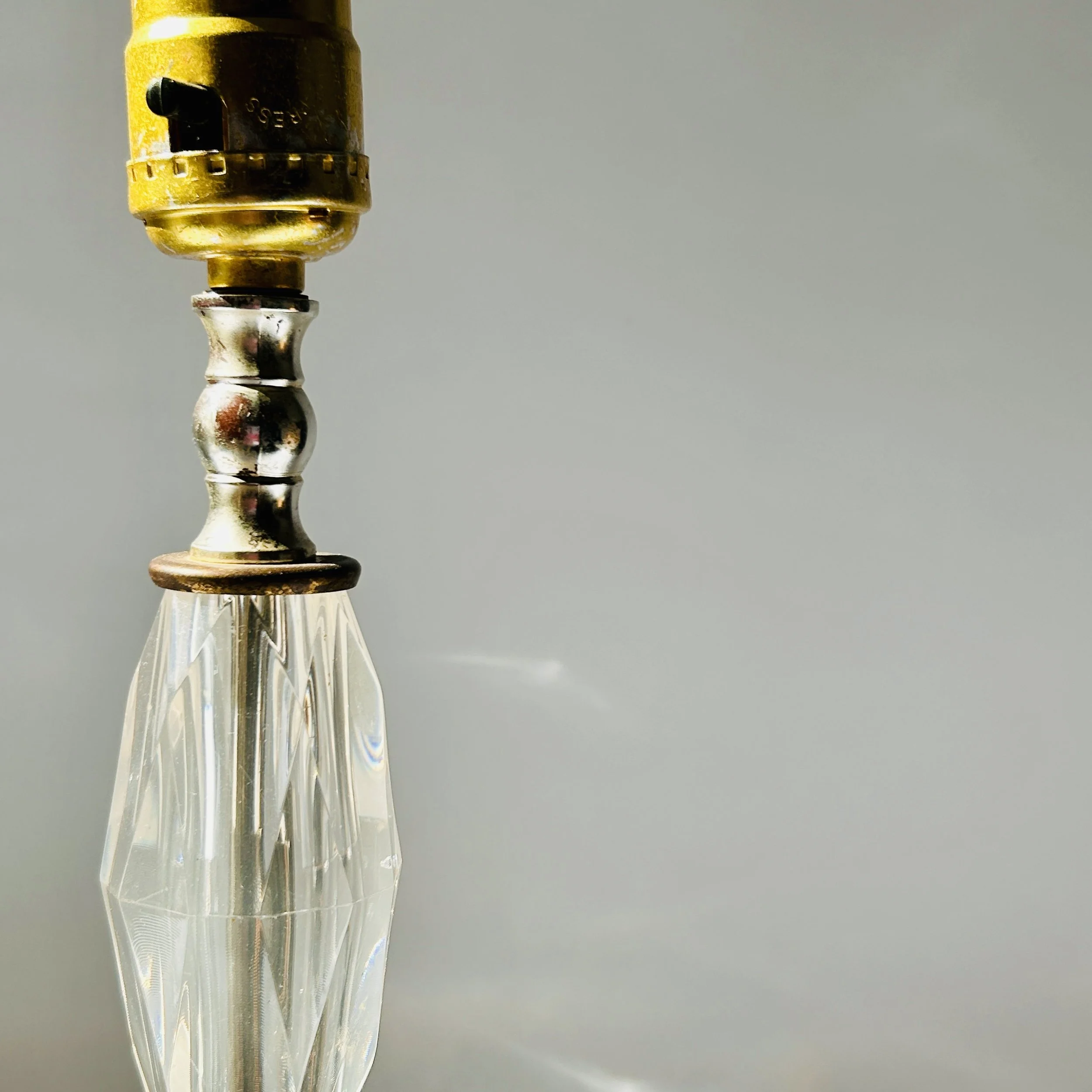 Vintage table lamp with faceted clear crystal-look elements, silver-tone metal accents, pale marble square base, and exposed red bulb.