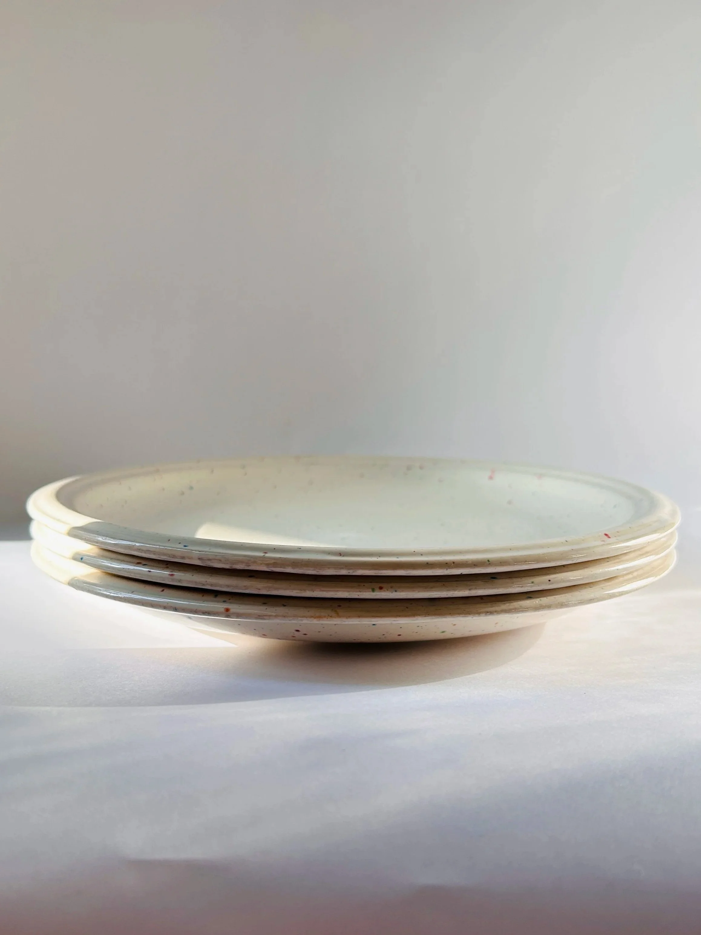 set of three cream stoneware plates with colorful confetti speckle pattern