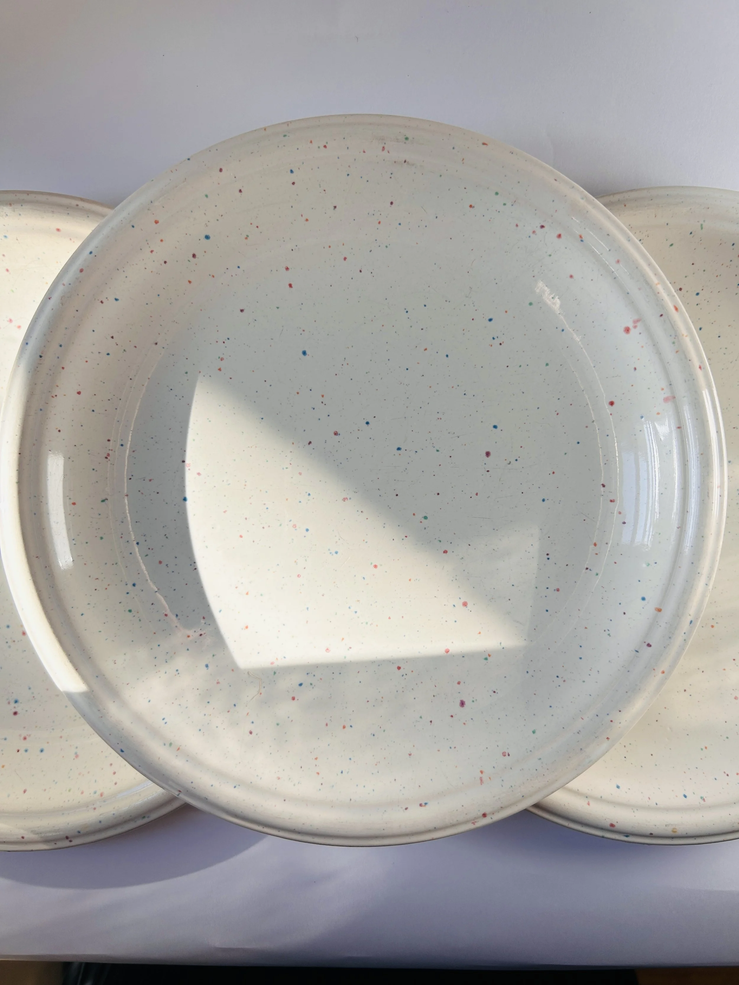 set of three cream stoneware plates with colorful confetti speckle pattern