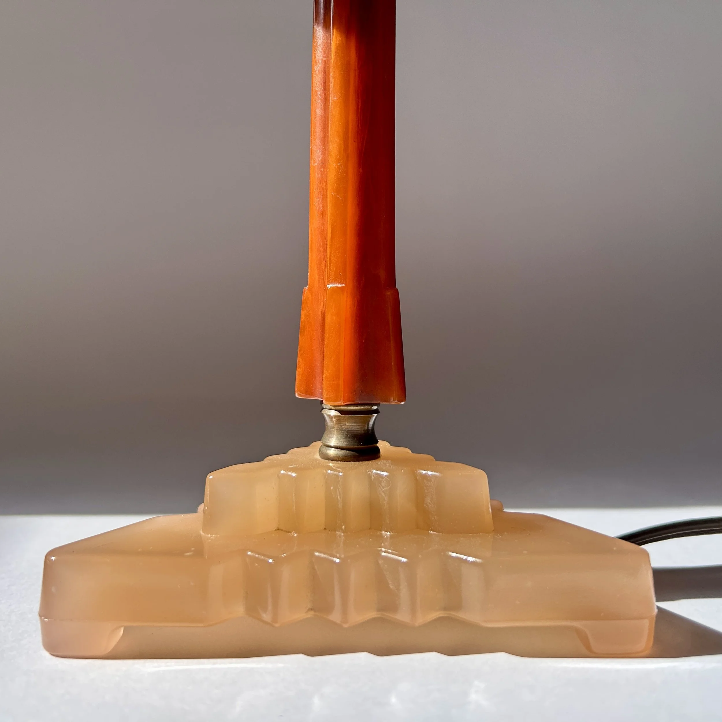 Vintage amber Bakelite table lamp with stepped geometric base, slender column, and warm brown floral lampshade.