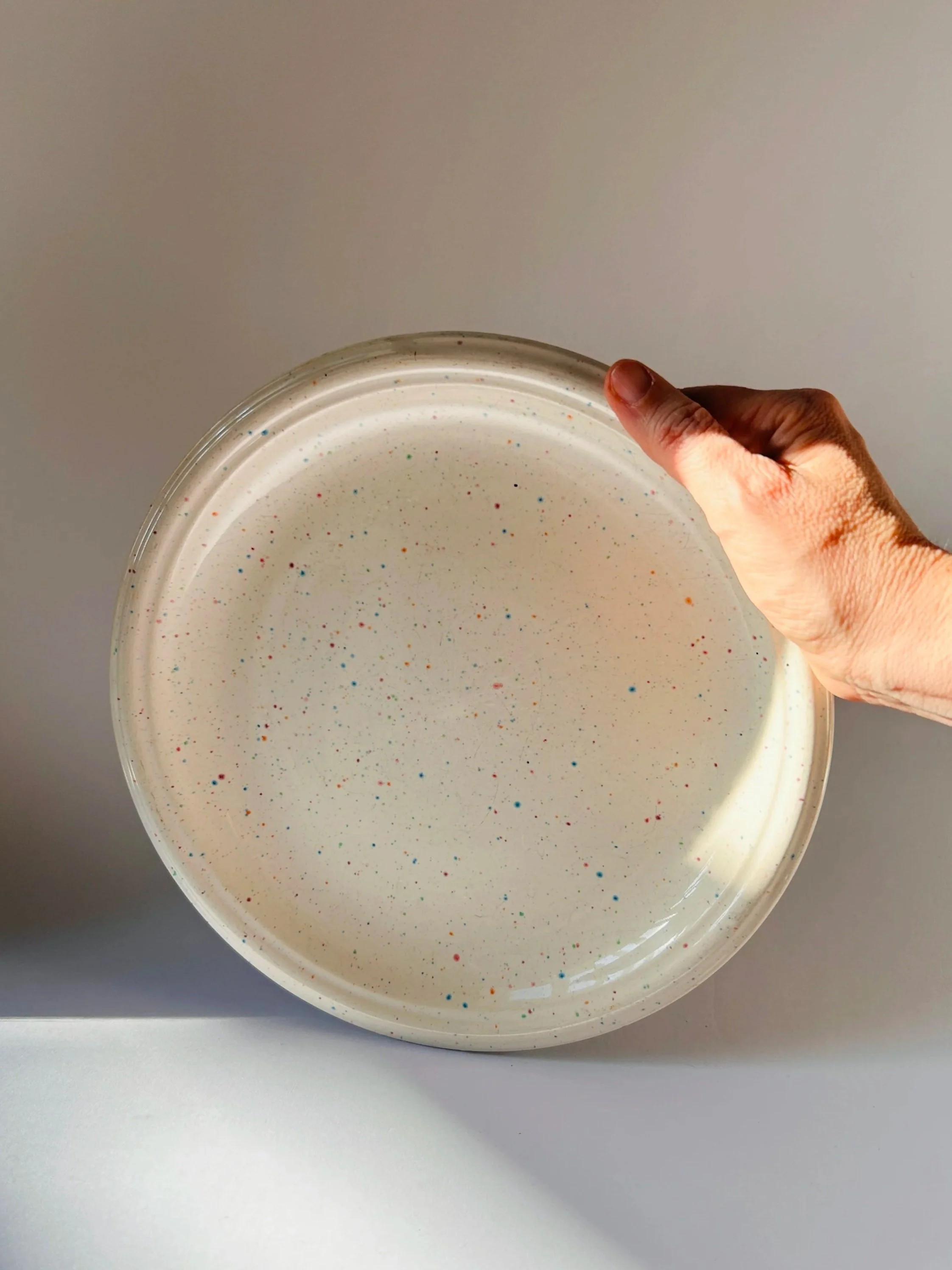 set of three cream stoneware plates with colorful confetti speckle pattern