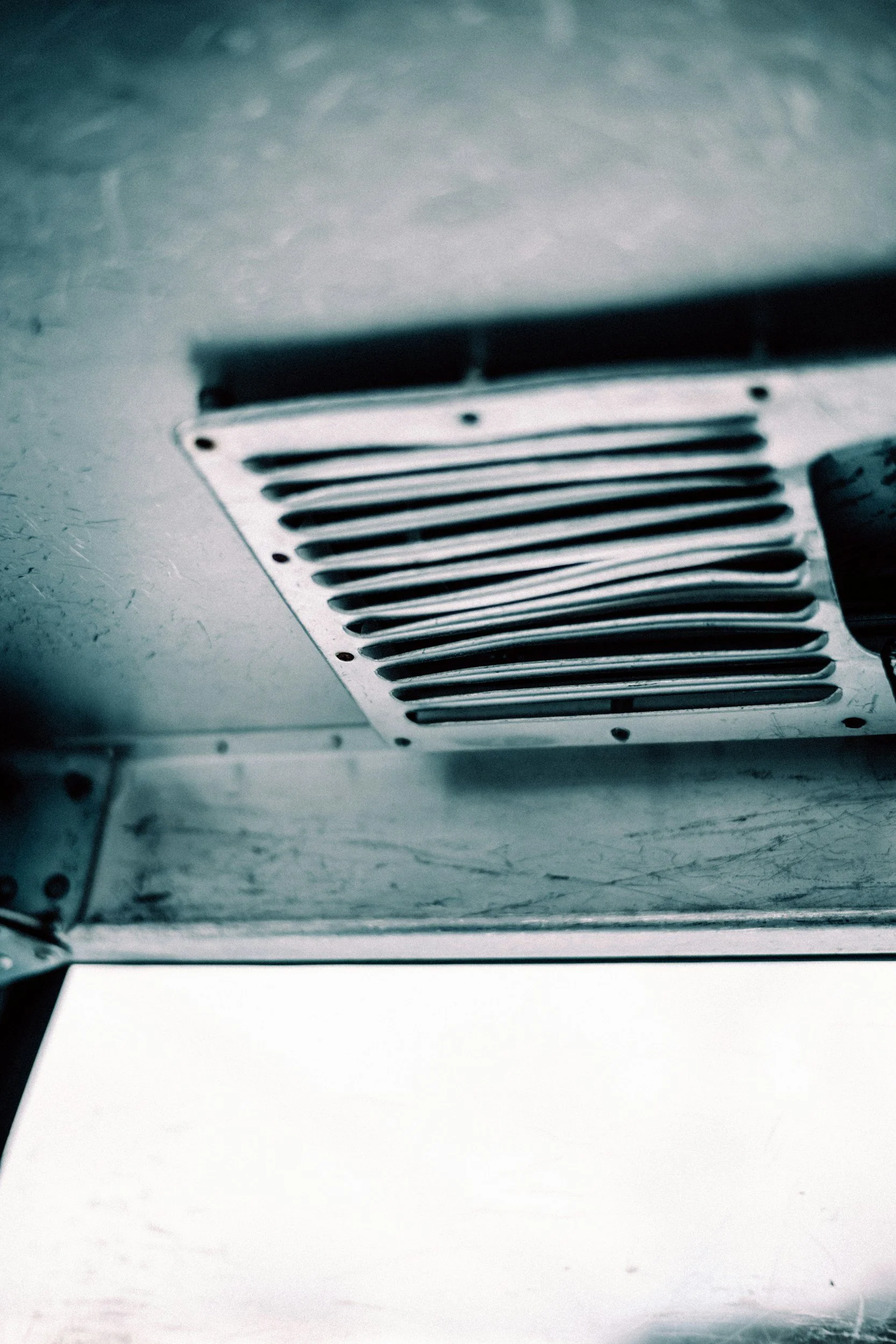 Close-up of a metal air vent or grille on a ceiling or wall.