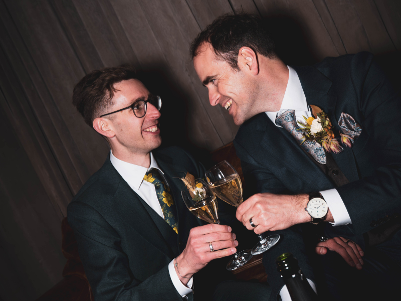 Two men in suits celebrating with champagne glasses