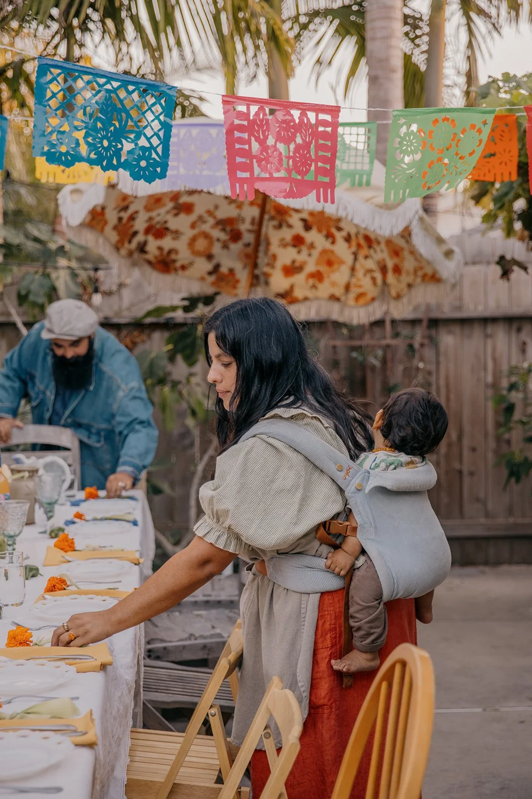 Woman setting table with baby on back