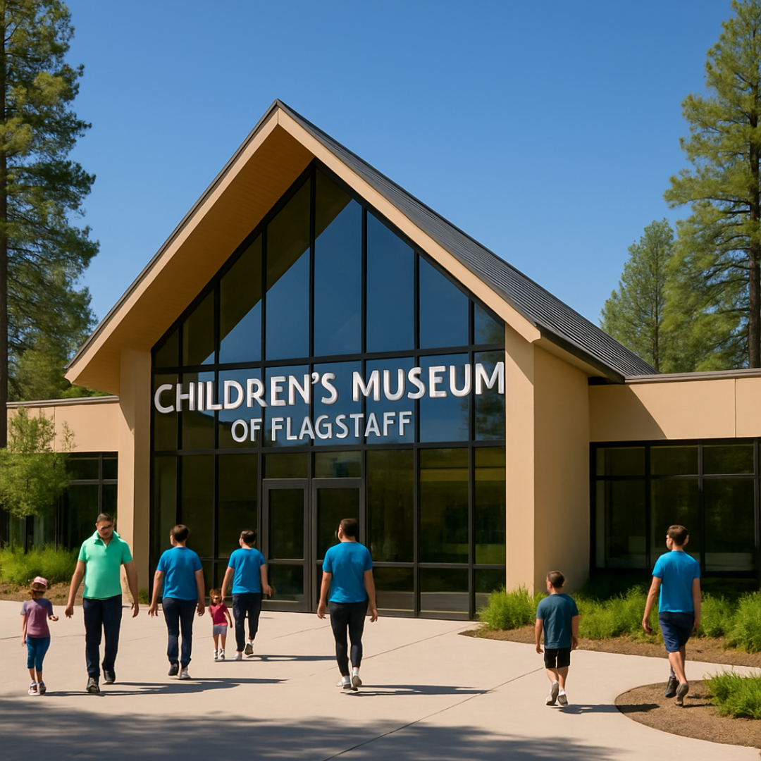 People walking towards the entrance of the Children's Museum of Flagstaff on a sunny day, surrounded by trees.