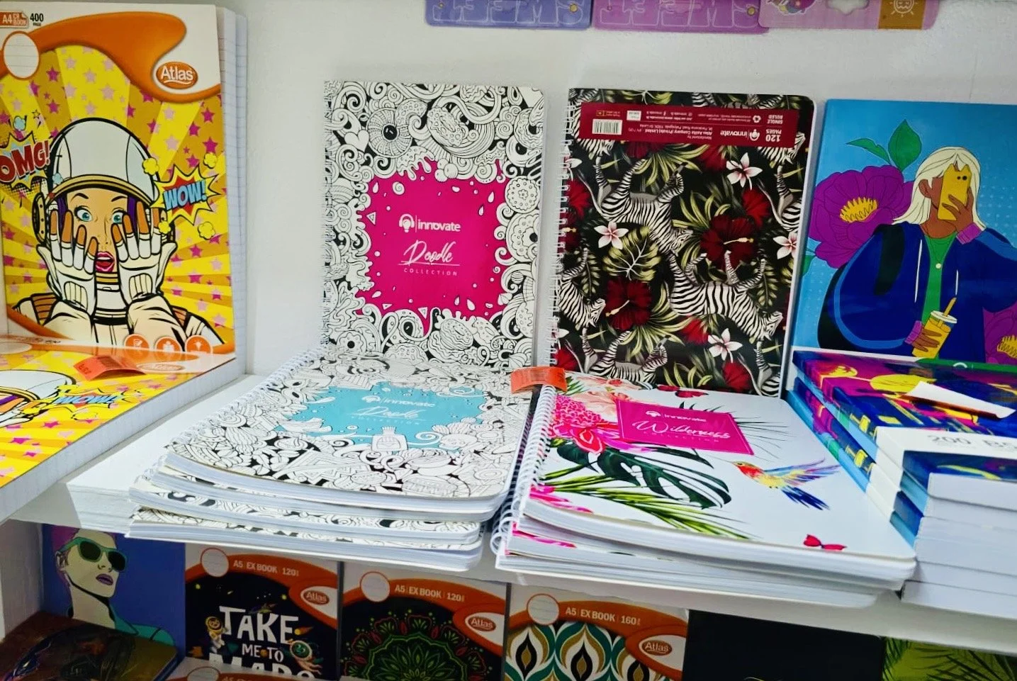 Colorful notebooks with various artistic and floral designs displayed on a store shelf.