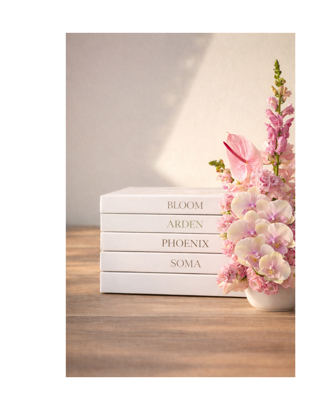 Stack of five white books with pastel-colored flower arrangements on a wooden surface.