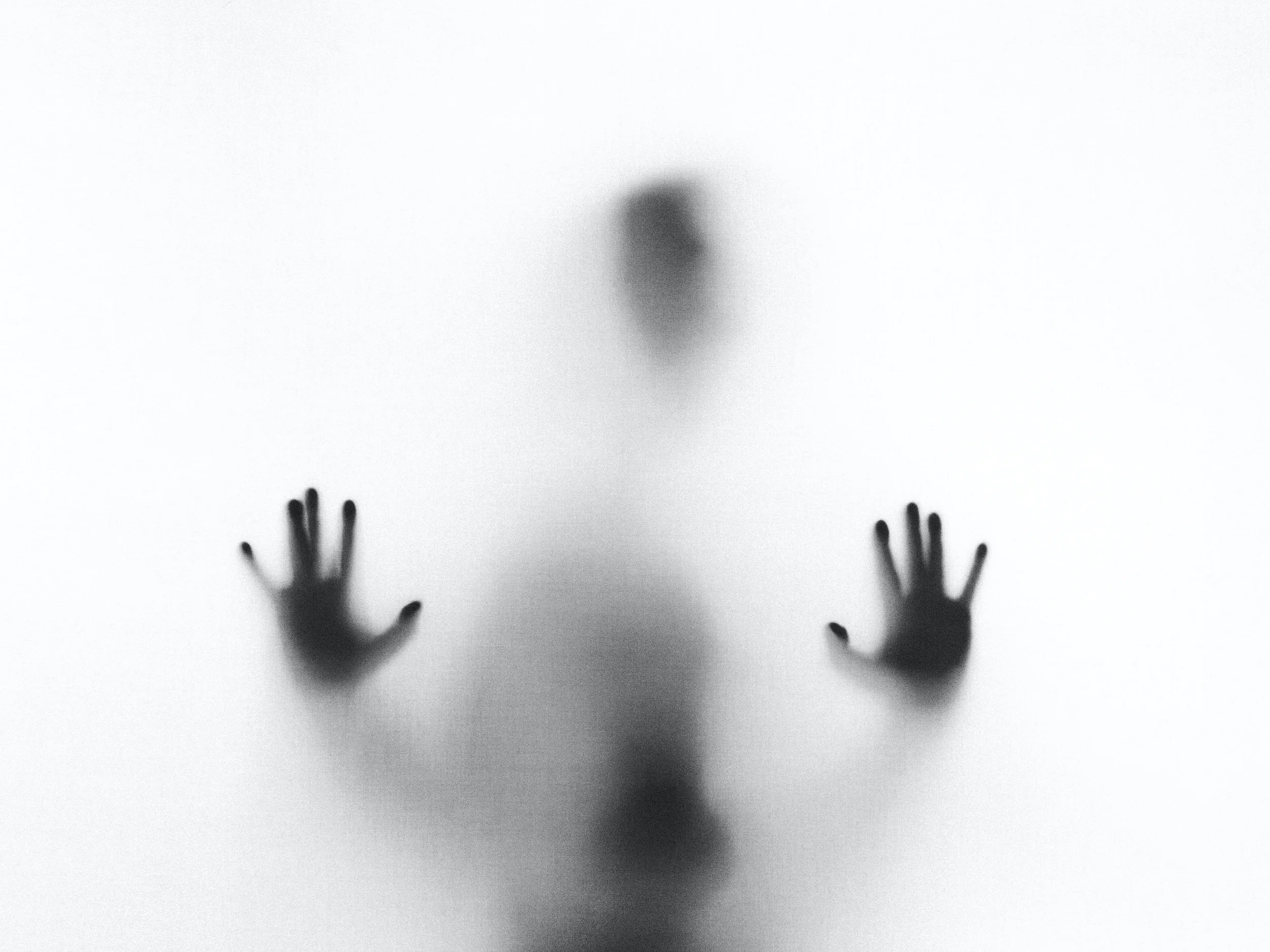 Dark figure resting hands on window.