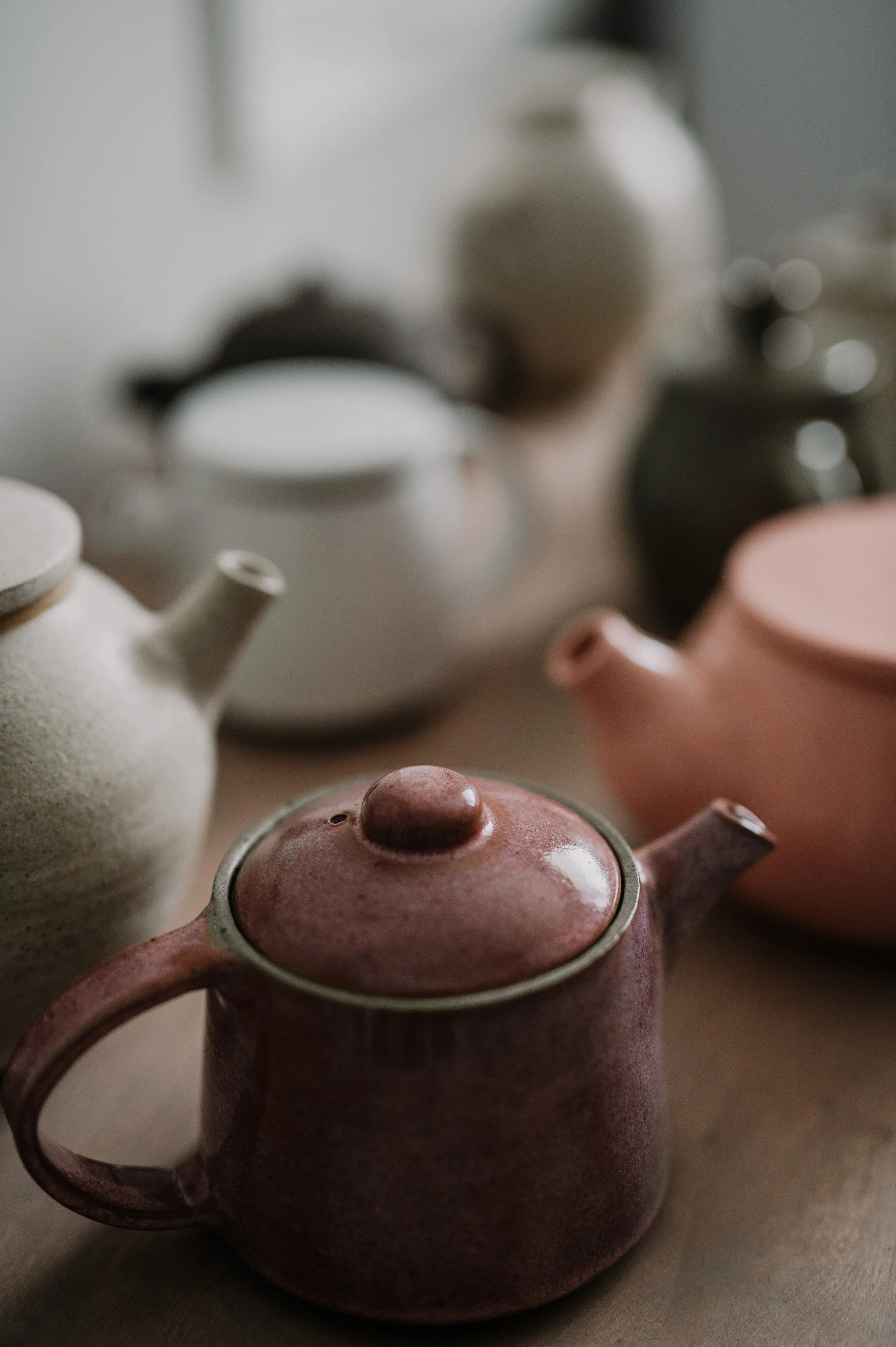 Various colorful ceramic teapots on a table with a blurred background.