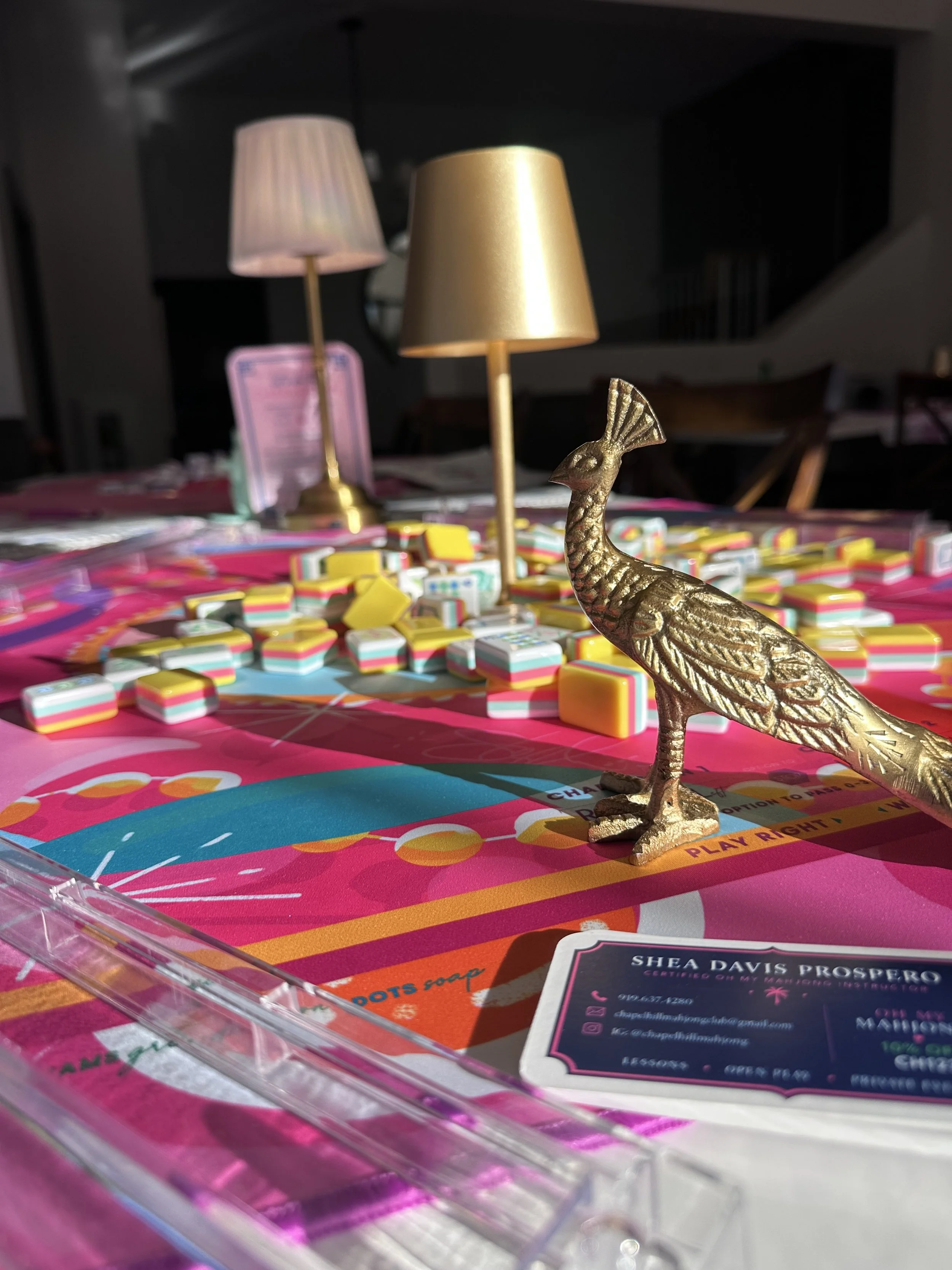 Pink Mahjong table with tiles, racks and a gold peacock at a Mahjong event