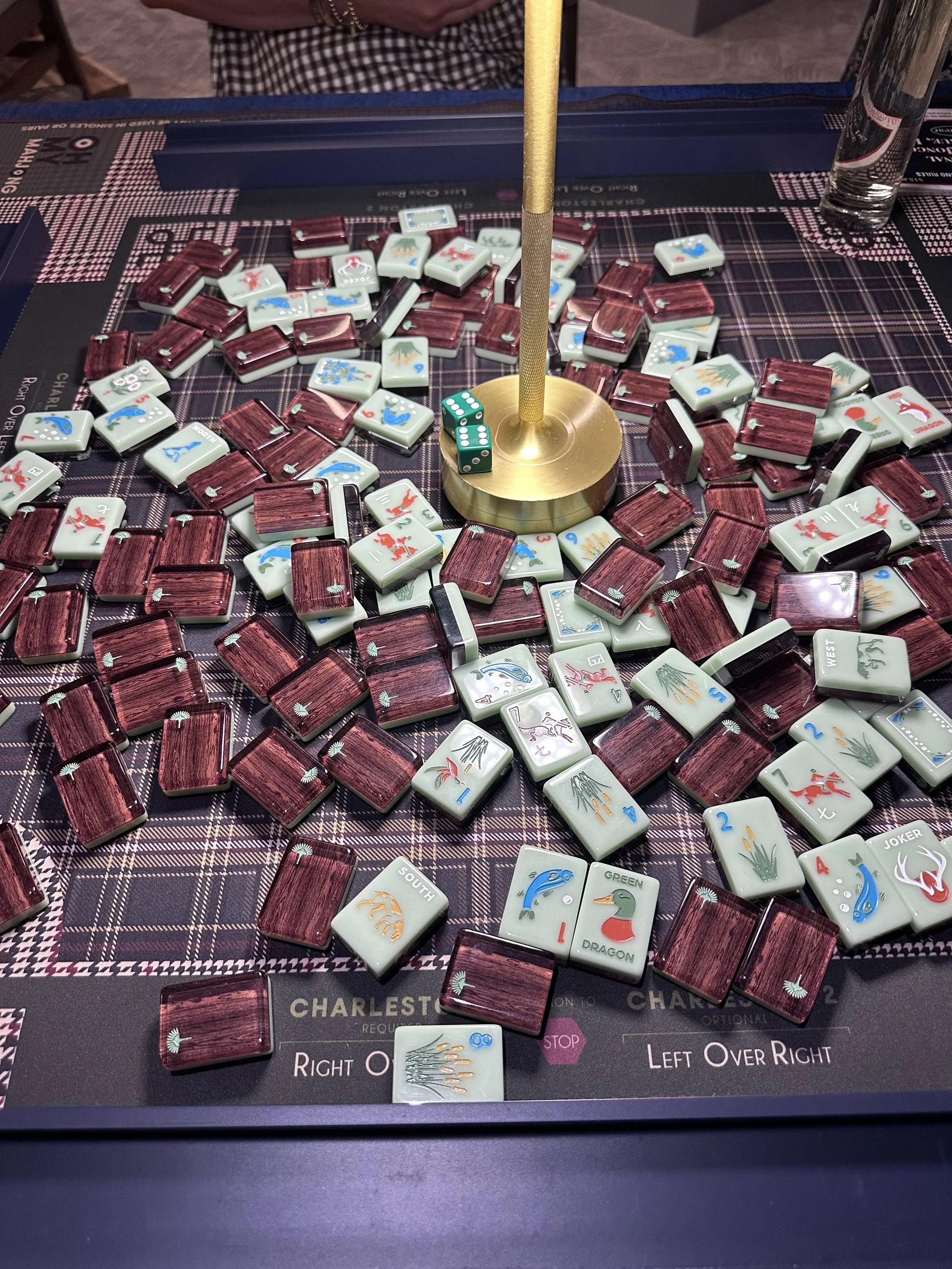 American Mahjong tiles on a plaid Mahjong mat with a gold lamp