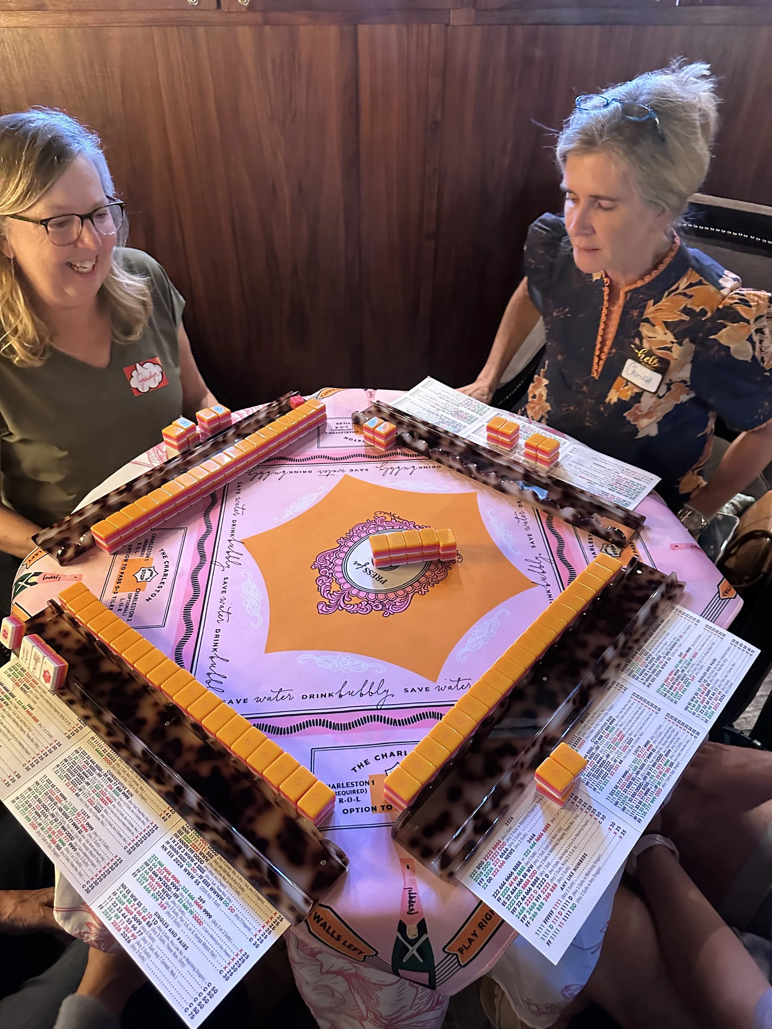 Players at an American Mahjong table with an orange and pink mat