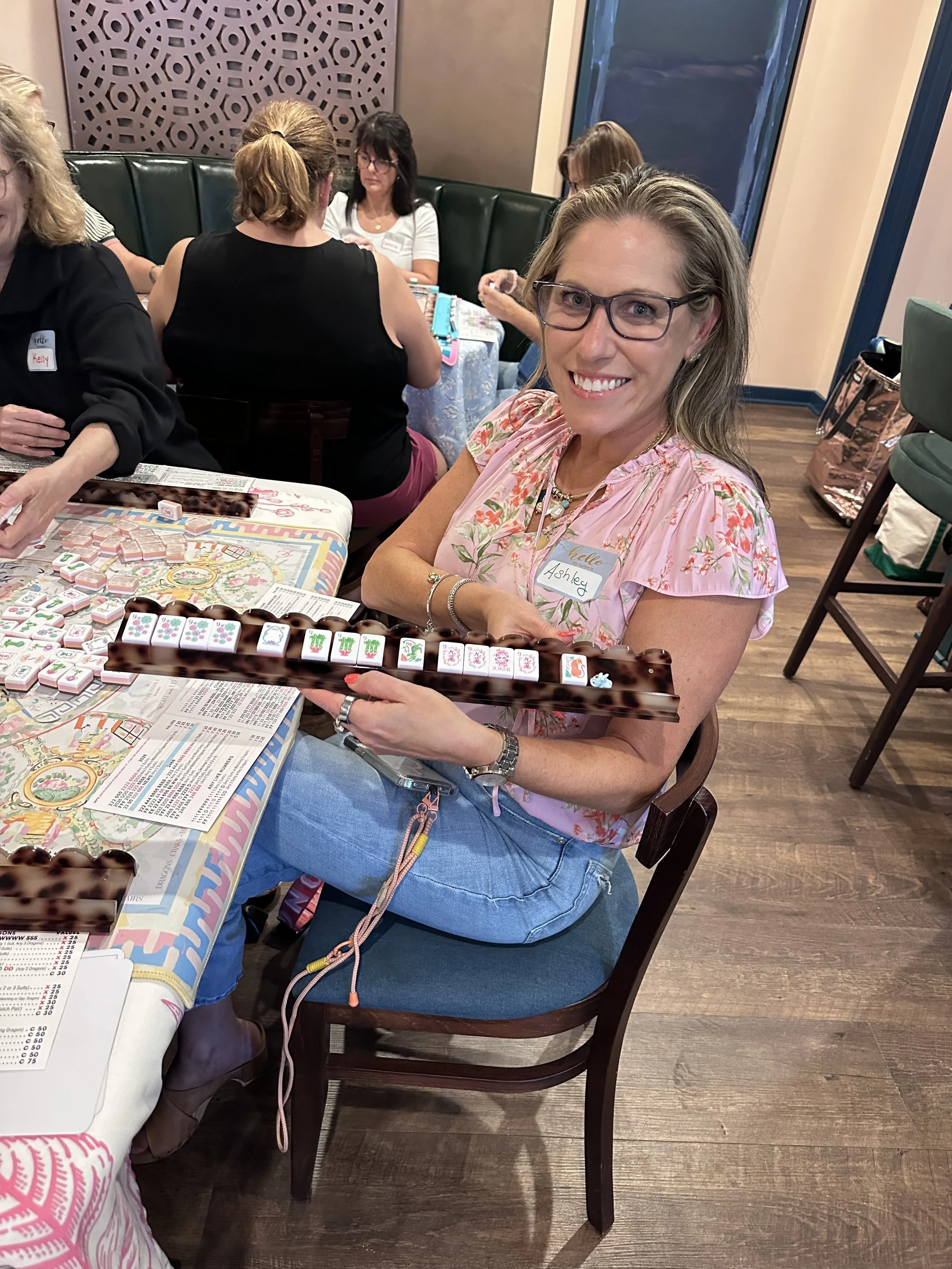 Smiling student holding her American Mahjong tiles at a Chatham County class