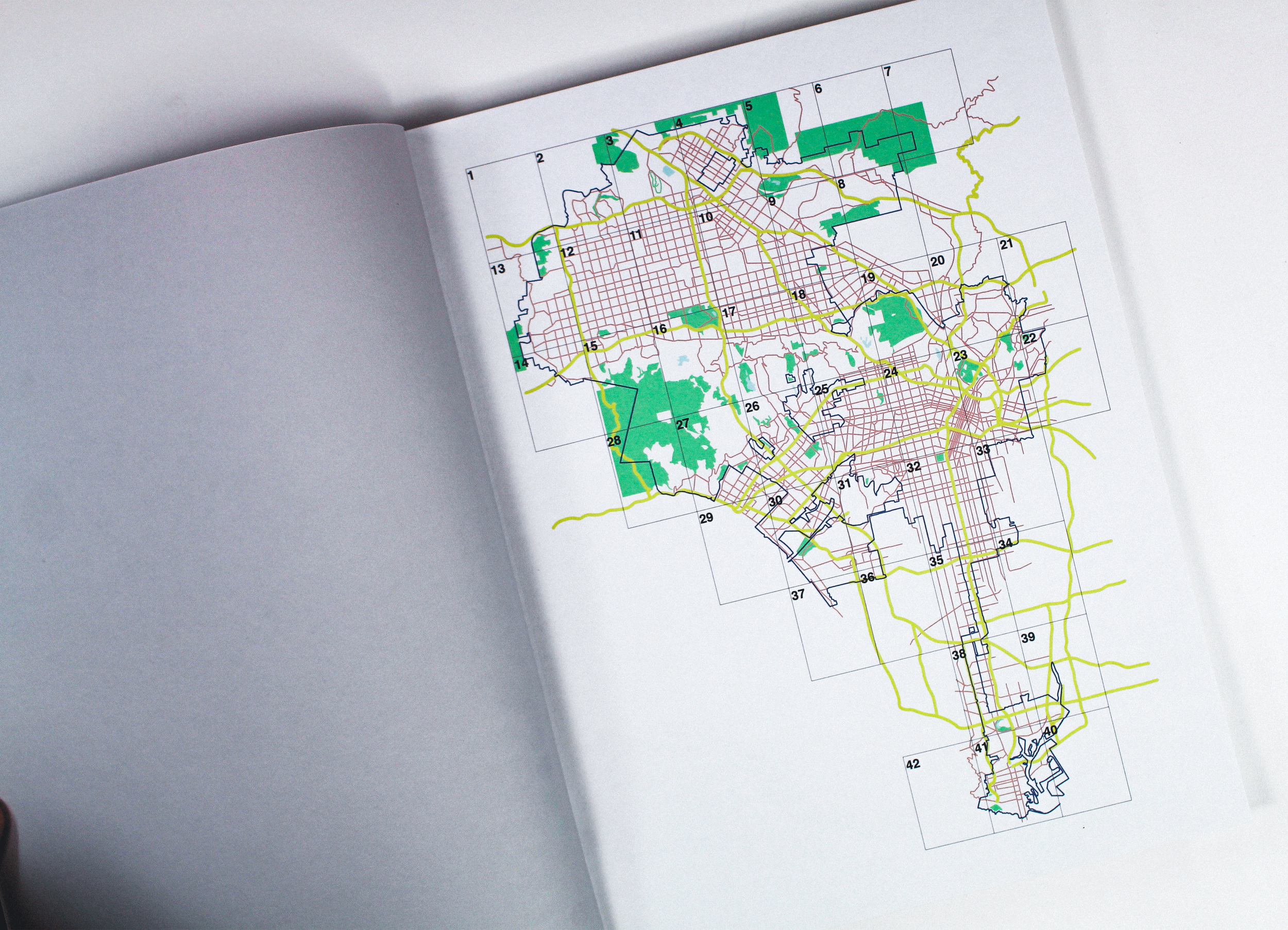 A detailed city map with numbered sections, streets marked in red, green areas representing parks, and yellow roads connecting different parts of the city.