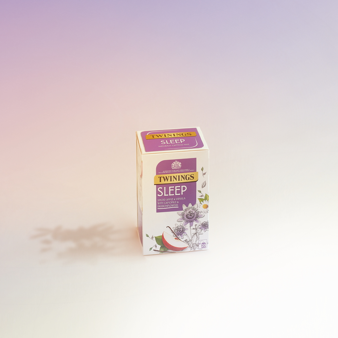 A box of Twinings Sleep herbal tea with flavors of spiced apple and vanilla, with chamomile and passionflower, on a light background.