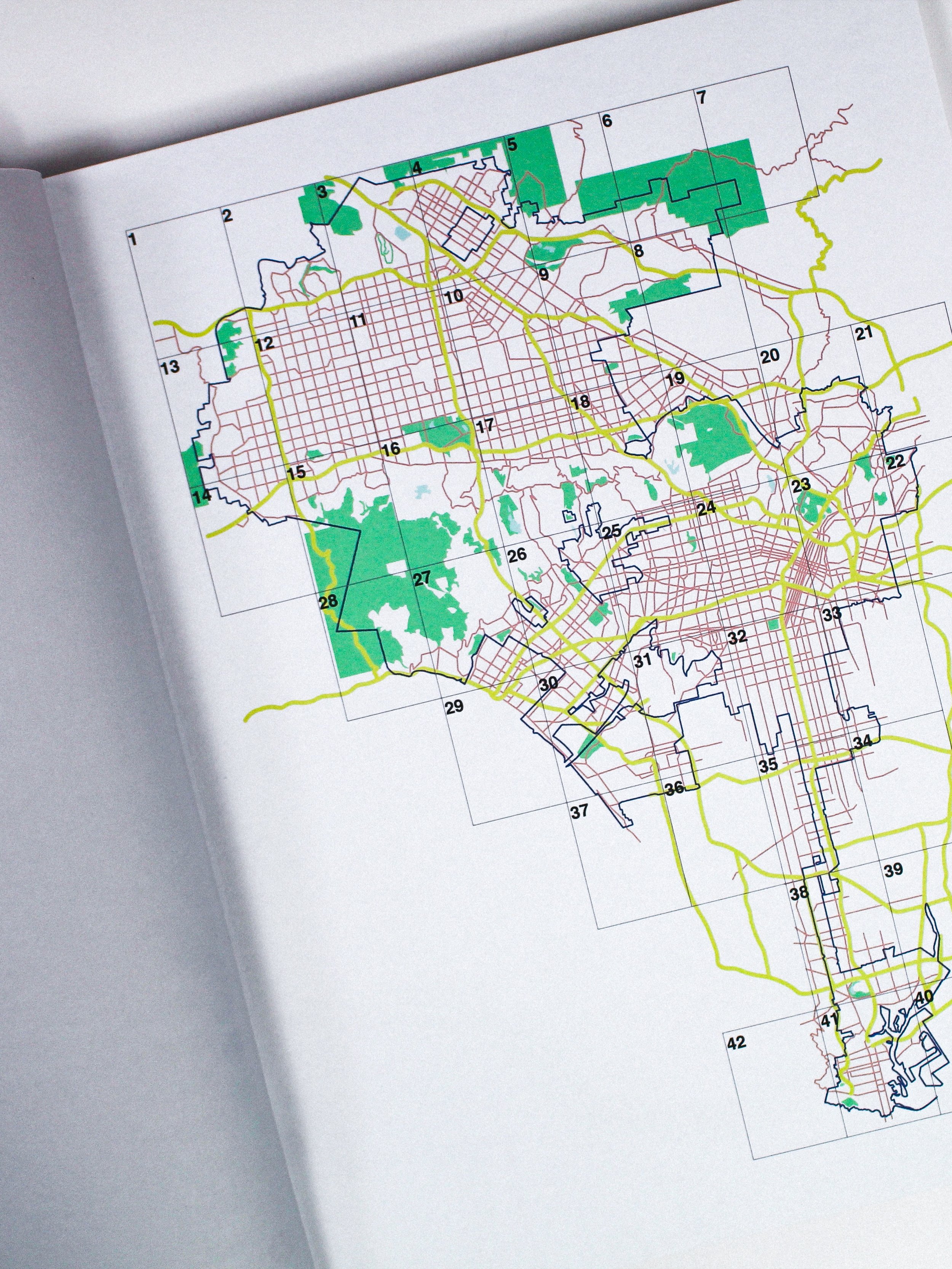 A detailed city map with numbered sections, streets marked in red, green areas representing parks, and yellow roads connecting different parts of the city.