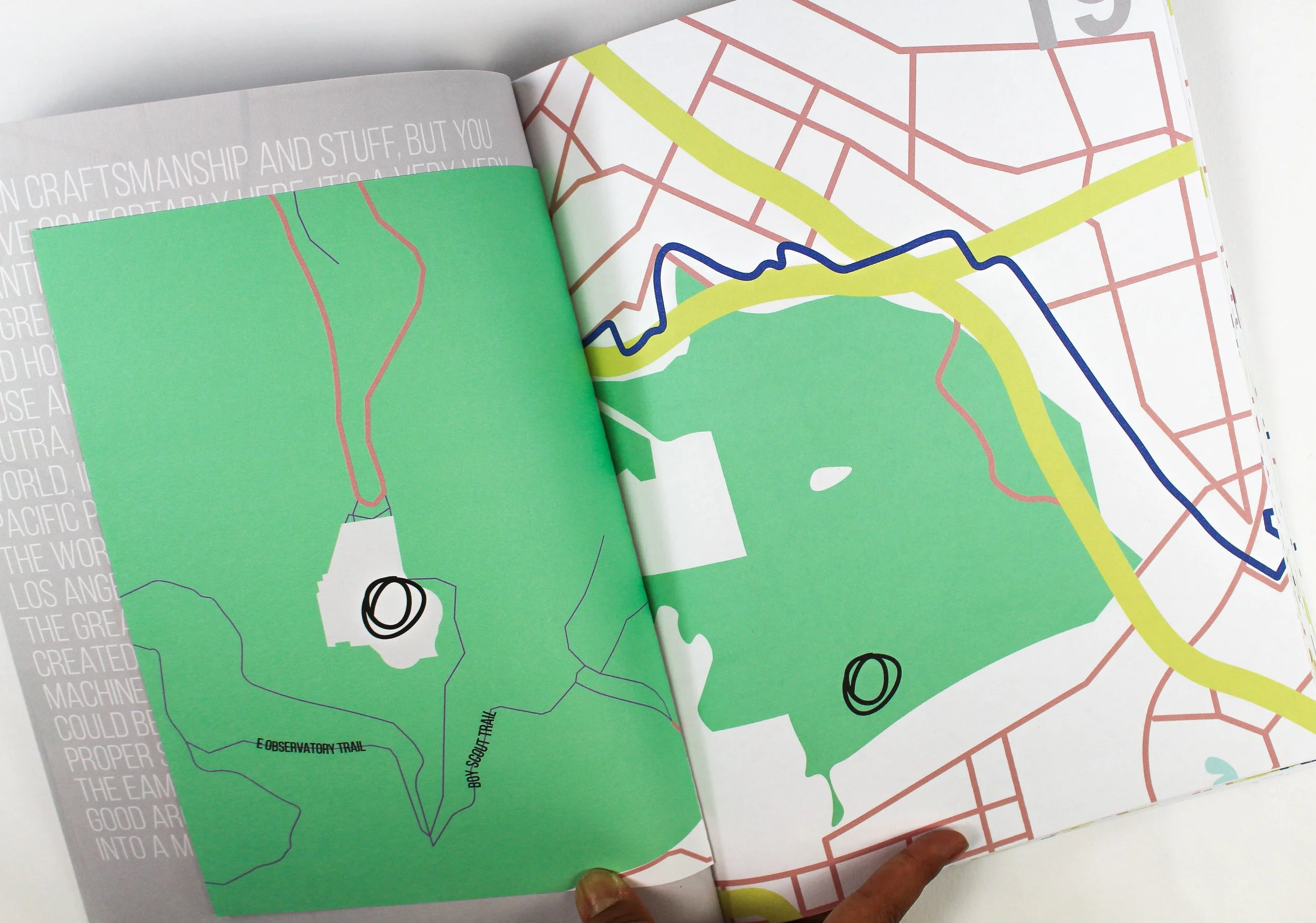 Open book showing two colorful maps of a park or trail system, one in green and one with marked routes, overlaid on a red grid map of a city area.