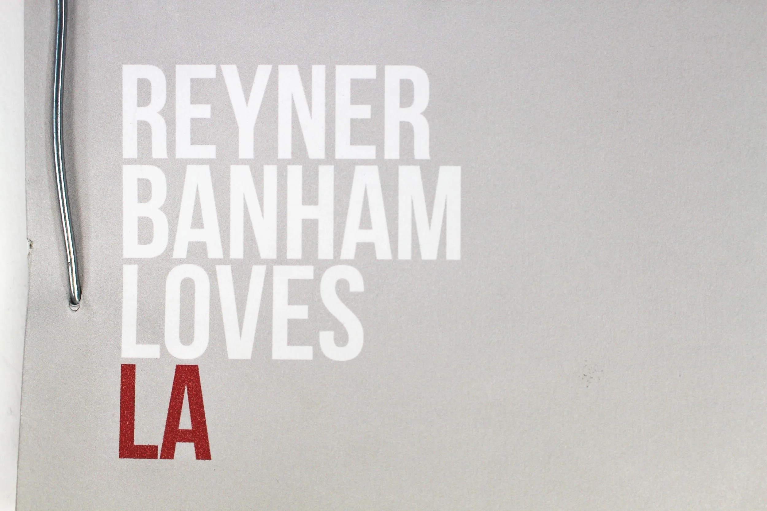 Close-up of the front of a book with white and red text, reading 'REYNER BANHAM LOVES LA'.