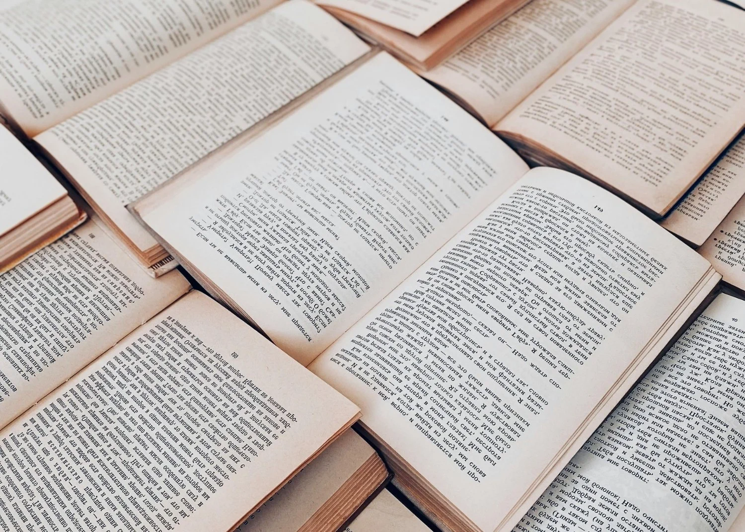Several open books with text, arranged in a flat lay, on a surface.