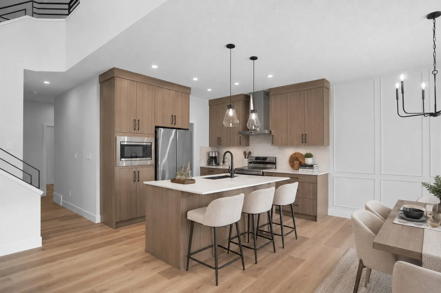 Modern kitchen with wooden cabinets, white countertops, stainless steel appliances, and a kitchen island with three beige bar stools.