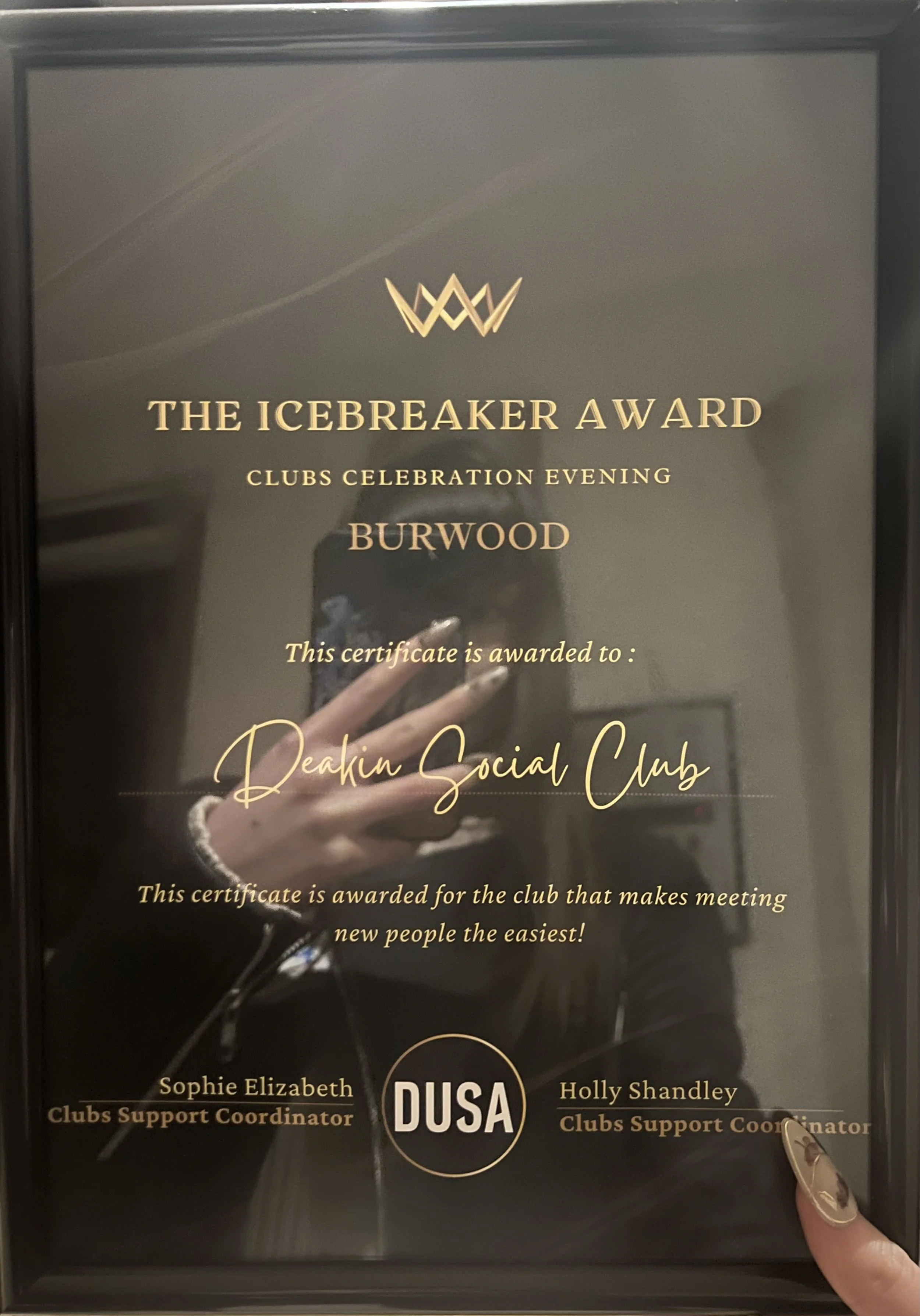 A framed certificate awarded to Deakin Social Club, with text indicating it was for an event called the Icebreaker Award during clubs celebration evening. The certificate is issued by DUSA and awarded to two club support coordinators, Sophie Elizabeth and Holly Shandley.