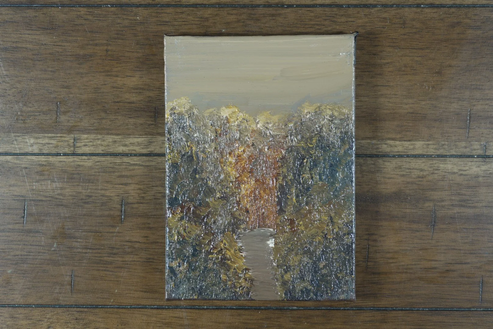 5x7 forest path oil painting on stretched canvas laid on a dark wood floor