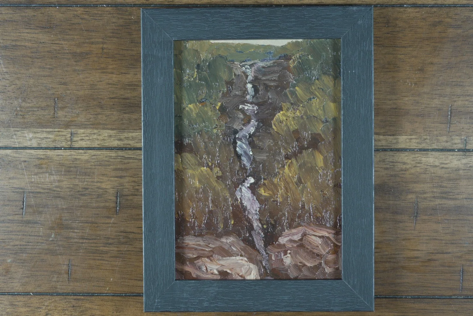 5x7 Gibbs Falls waterfall oil painting in a black wood frame on a dark wood floor