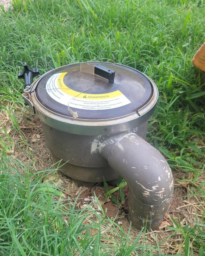 An underground water valve or meter in a grassy area.