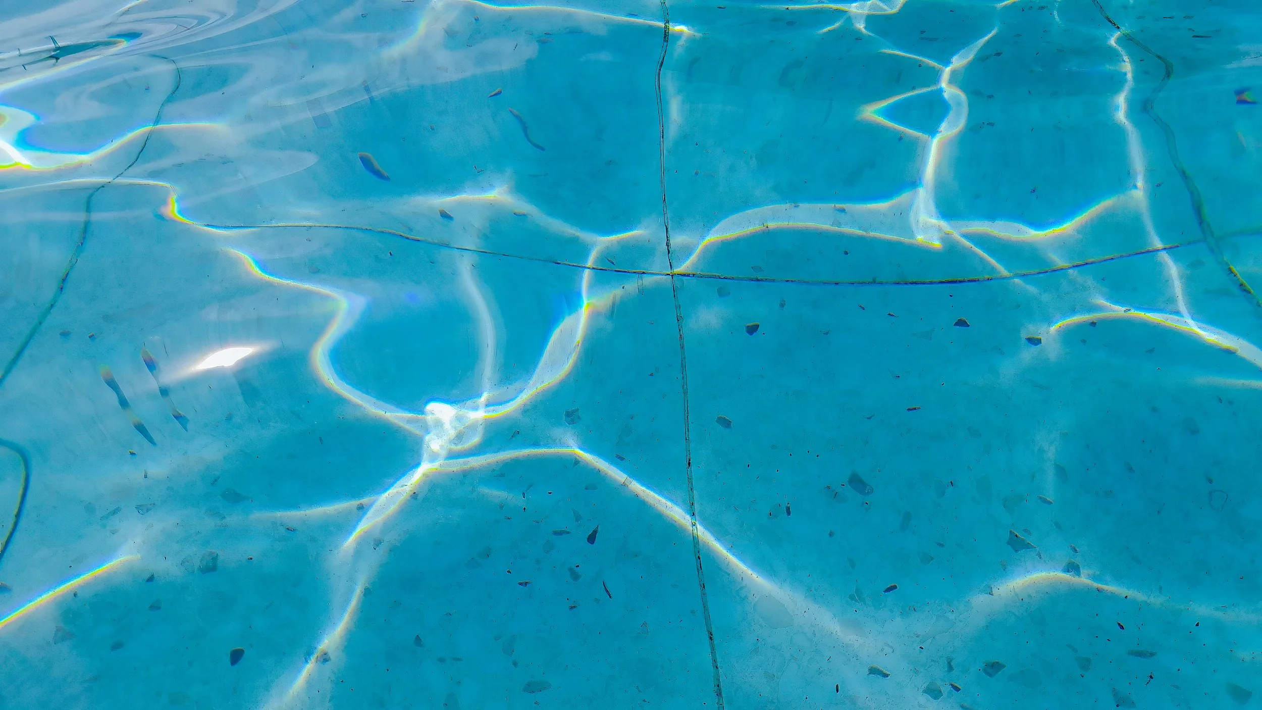 Close-up of a swimming pool with rippling water and reflections of sunlight.