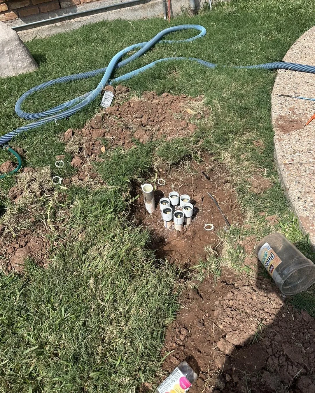 Underground sprinkler system installation with pipes and connectors in a garden.