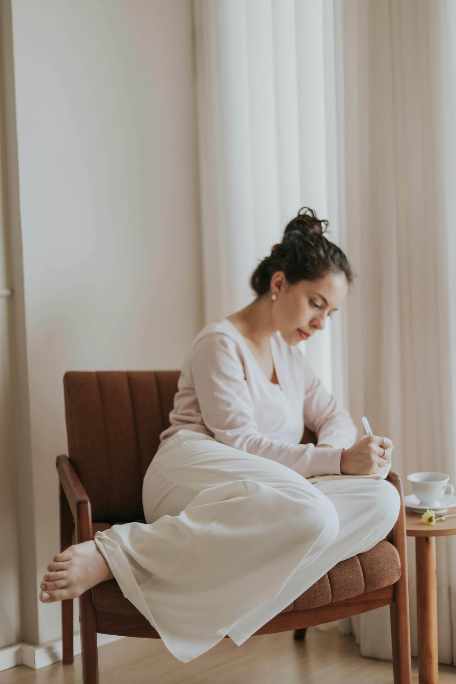 Woman sitting quietly and journalling in a calm space, representing stillness and readiness for inner work