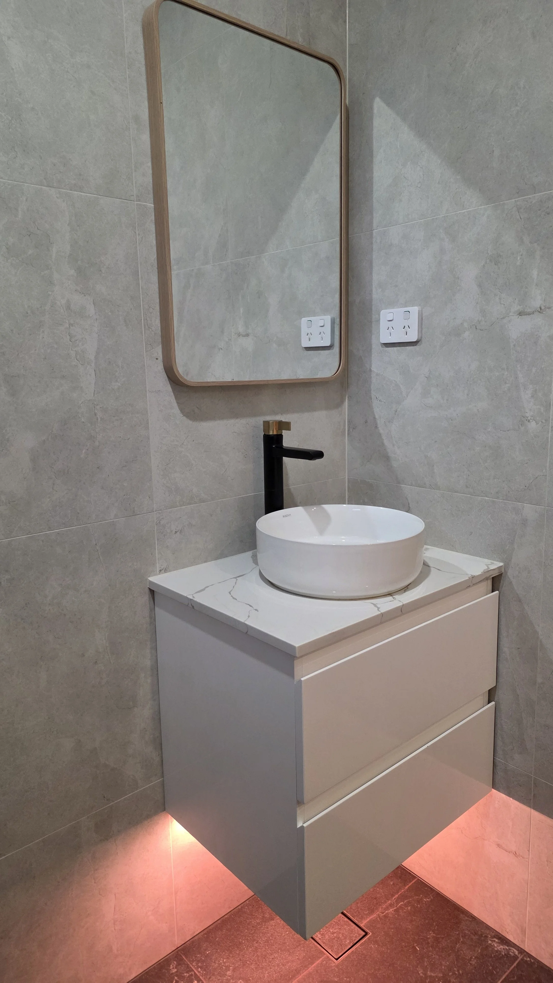 The ensuite bathroom features a rain shower and handheld shower, toilet, heater, exhaust fan, and ambient evening lighting beneath the vanity unit for a relaxing atmosphere.