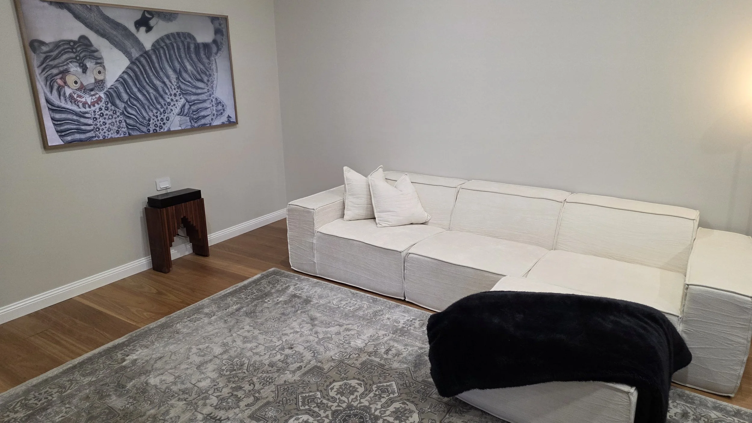 The living area includes a comfortable couch for four people, complete with a movable ottoman, throw blanket, and cushions for added comfort.