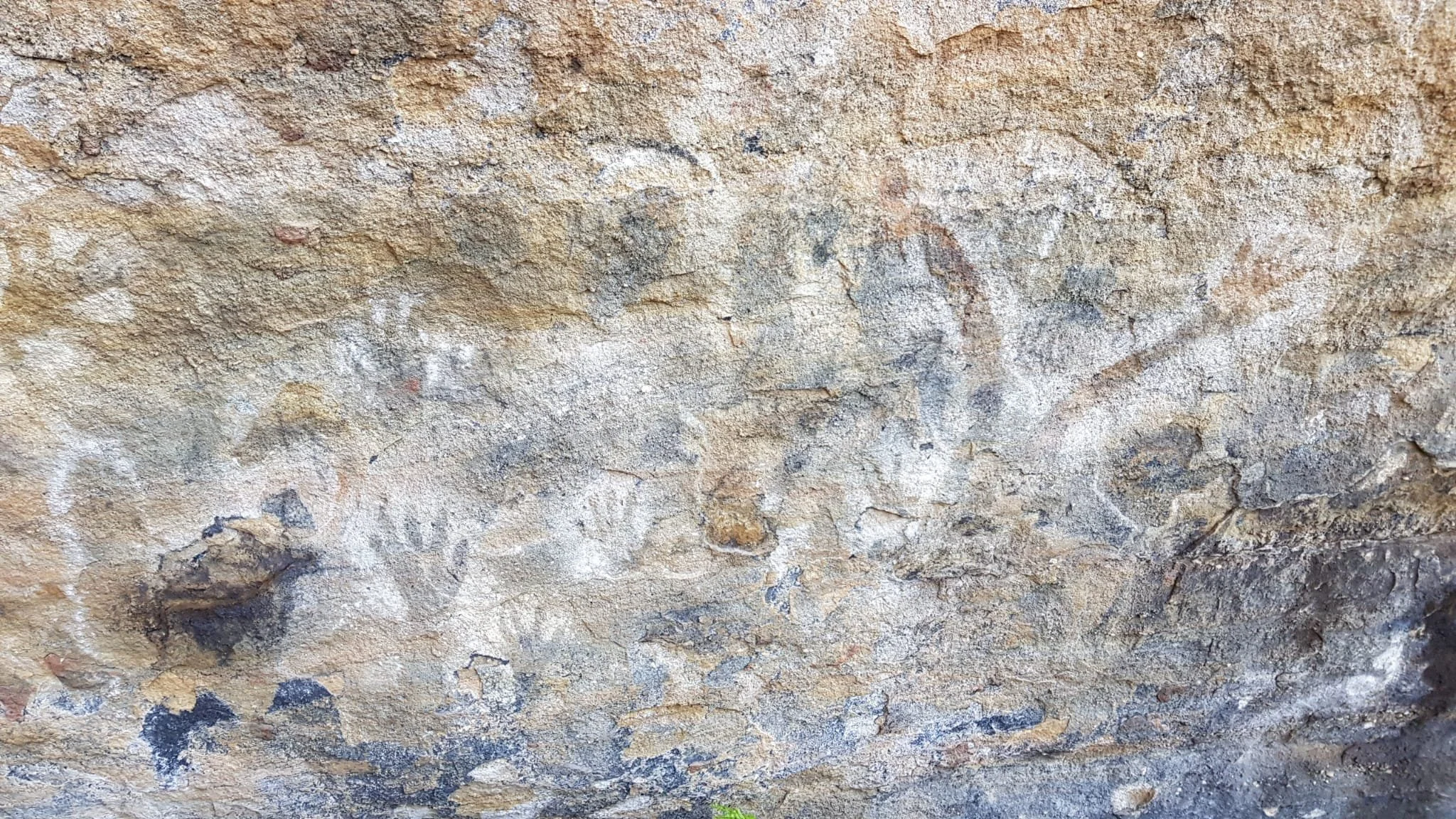 Close-up of a textured, weathered stone or concrete surface with various cracks and color variations.