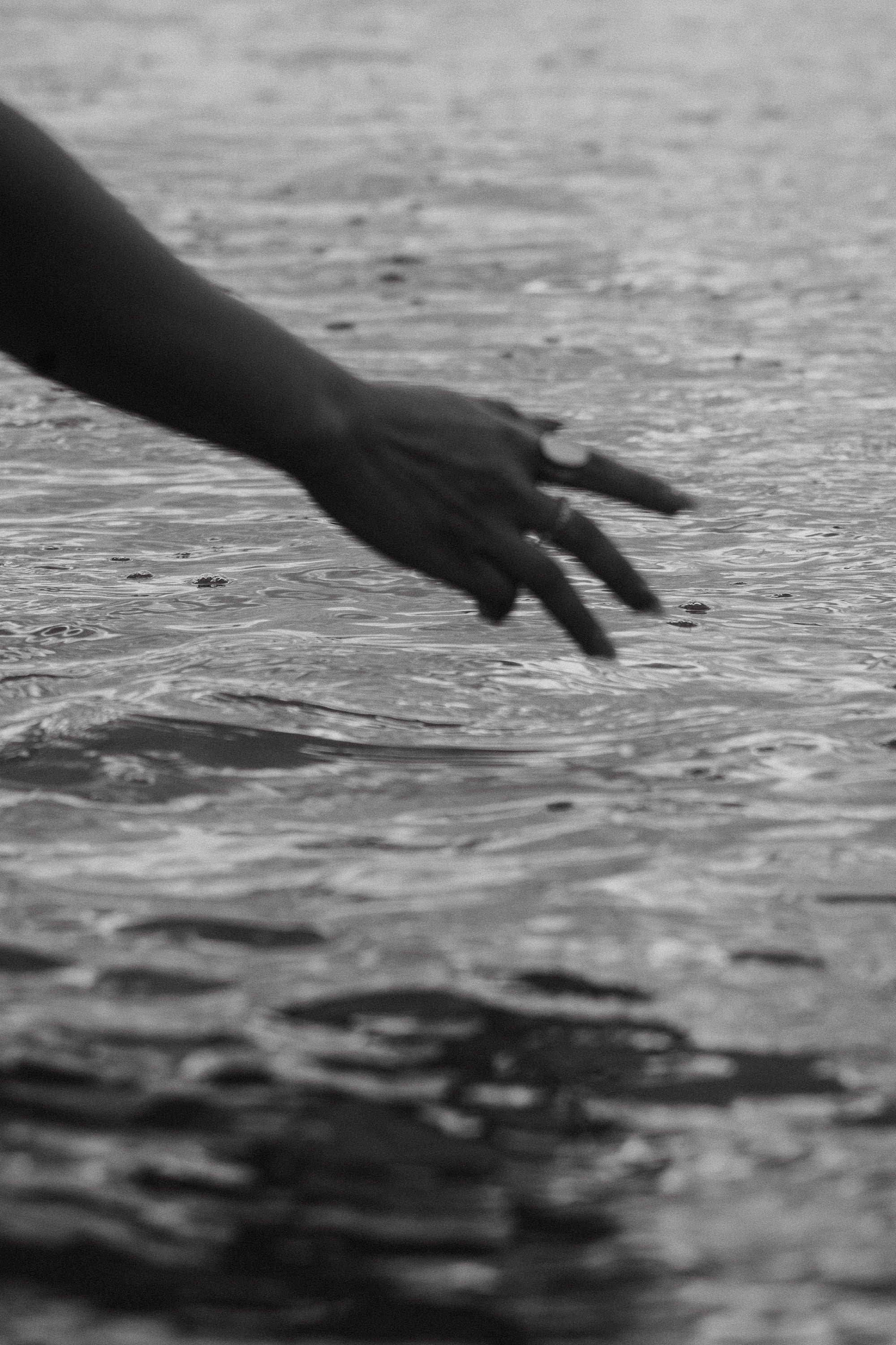 A hand reaching into water near the shoreline.