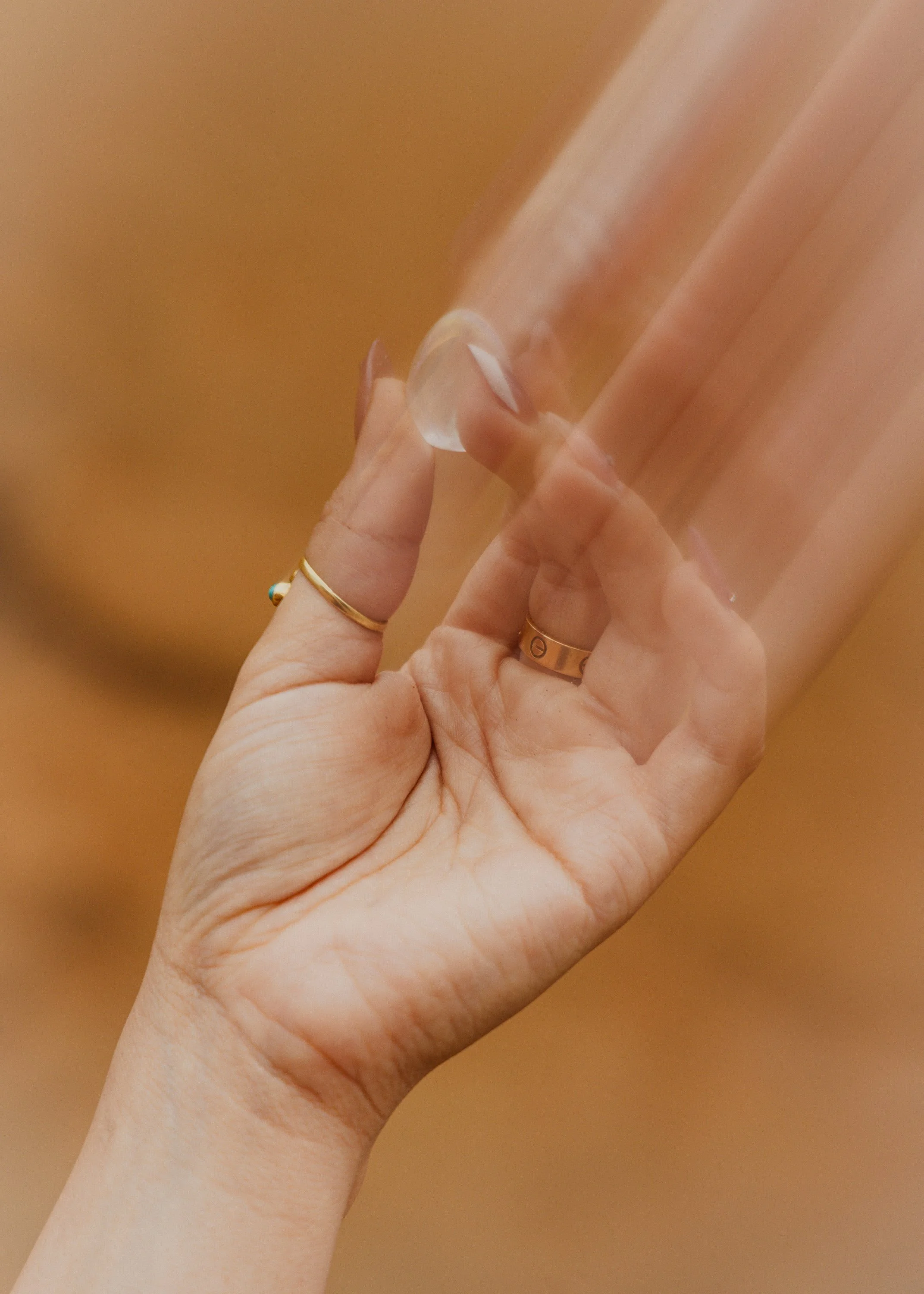 A person's hand holding a clear glass of water against a beige background.