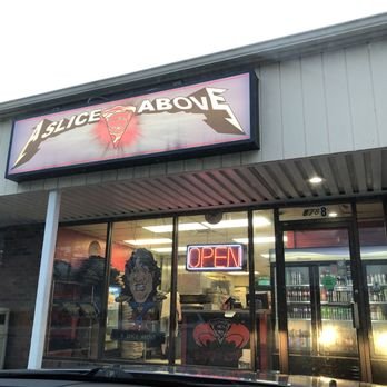 View of a storefront with a sign that reads 'Slice Above' and an illuminated 'Open' sign in the window.