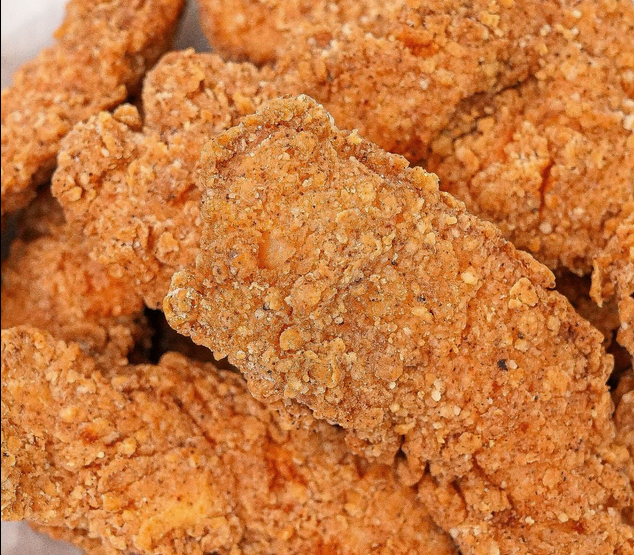Close-up of fried chicken tenders with crispy, seasoned breading.