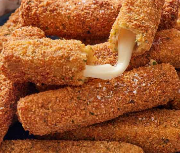 Close-up of mozzarella sticks being dunked in melted cheese.