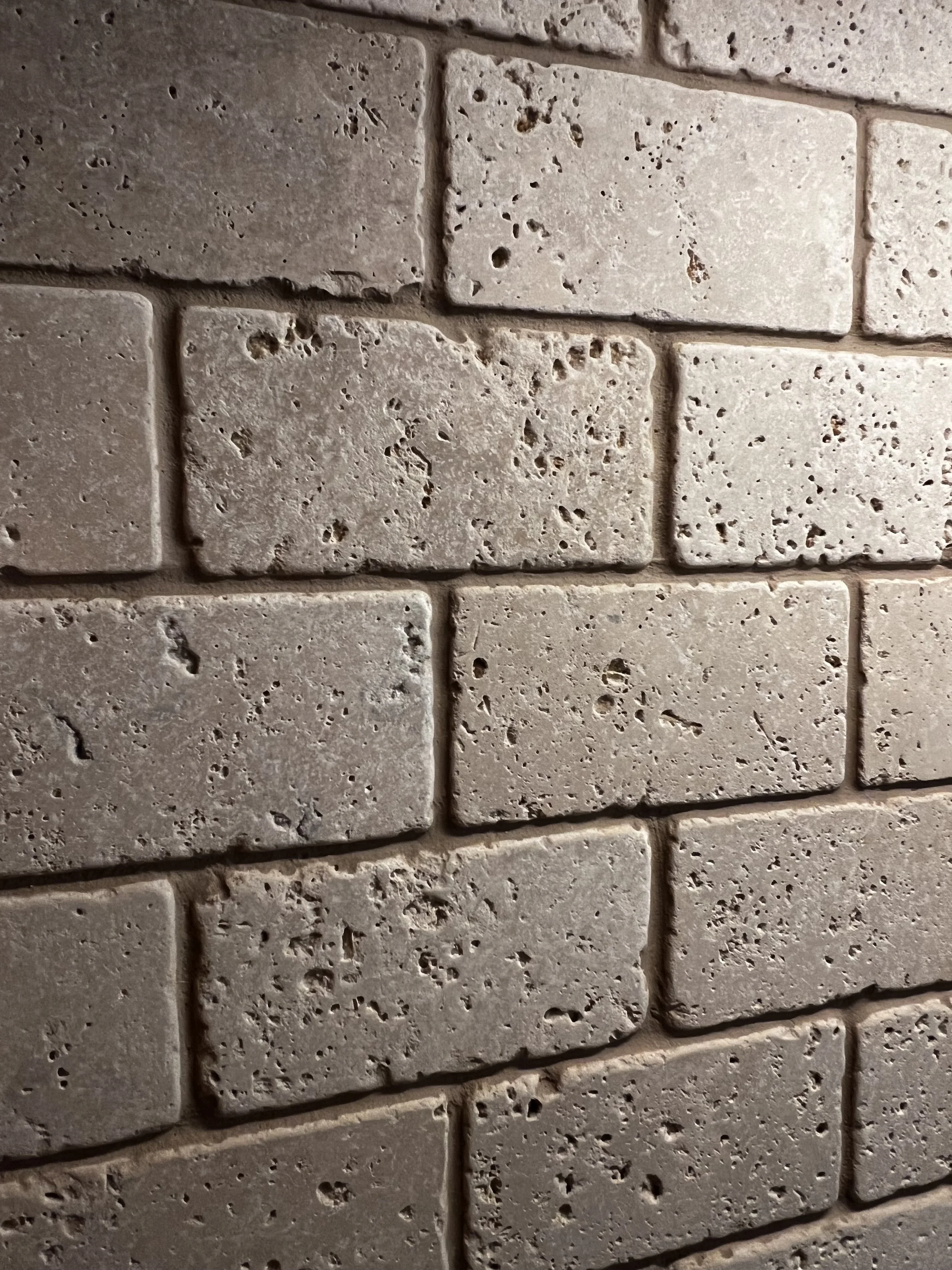 Close-up of beige brick wall with textured surface and mortar joints.