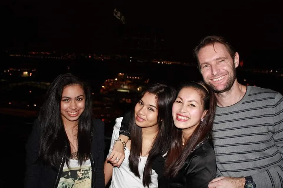 Four friends smiling at night with city lights in the background