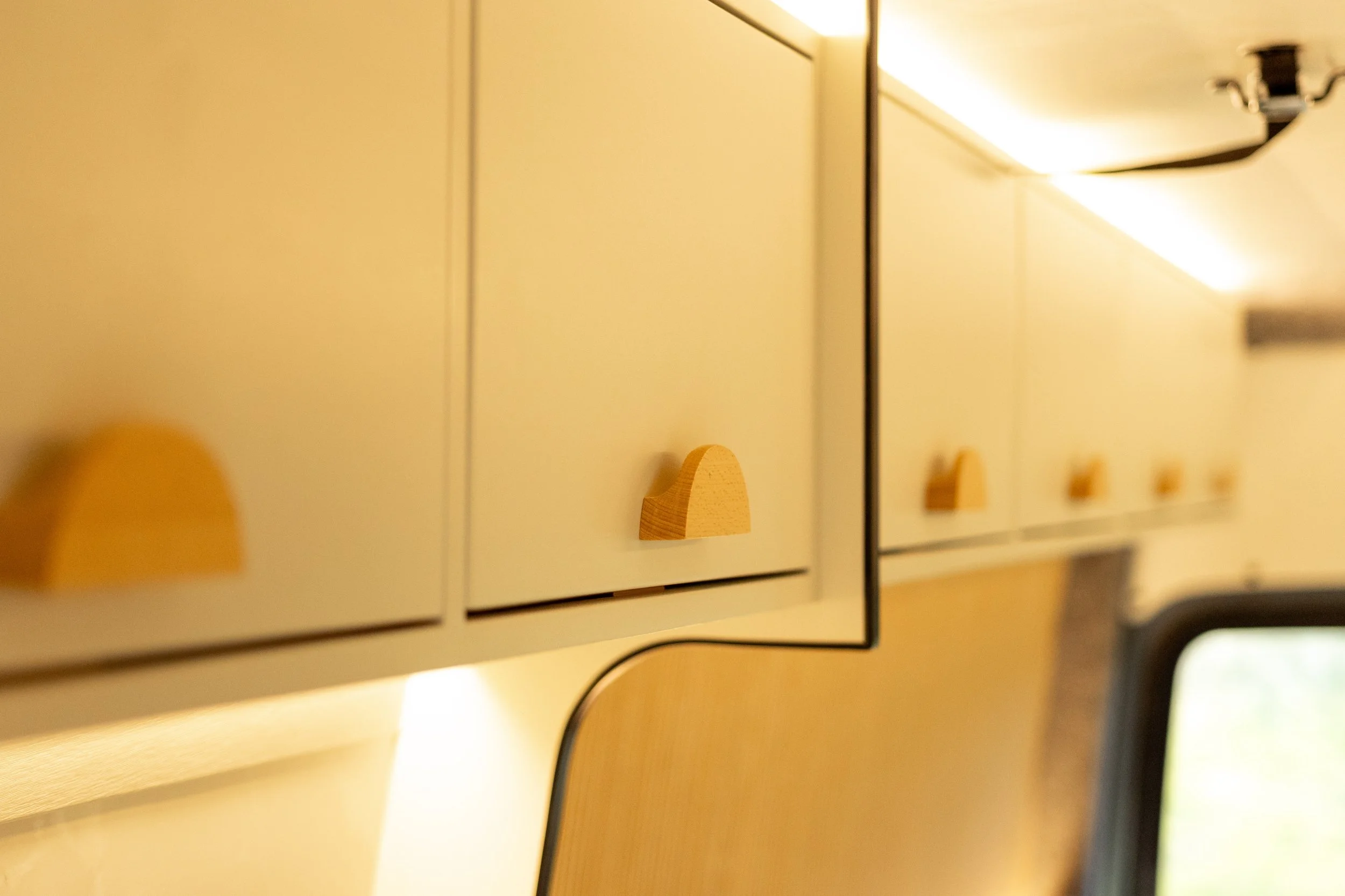 Close-up view of yellow kitchen cabinets with wooden handles and a section of a ceiling with a light fixture.