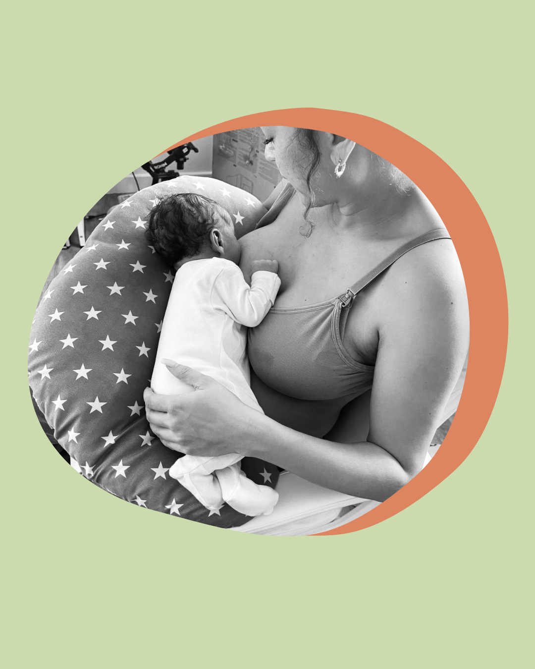 Black and white photo of a woman breastfeeding a newborn baby, who is lying on a pillow with star patterns.