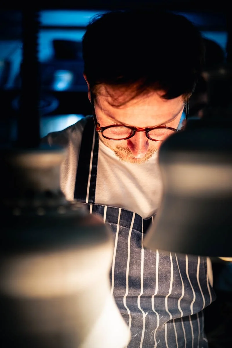Chef Rafael Amsler working at the pass, between two heating lamps, at VDB Bistronomie, Lisbon
