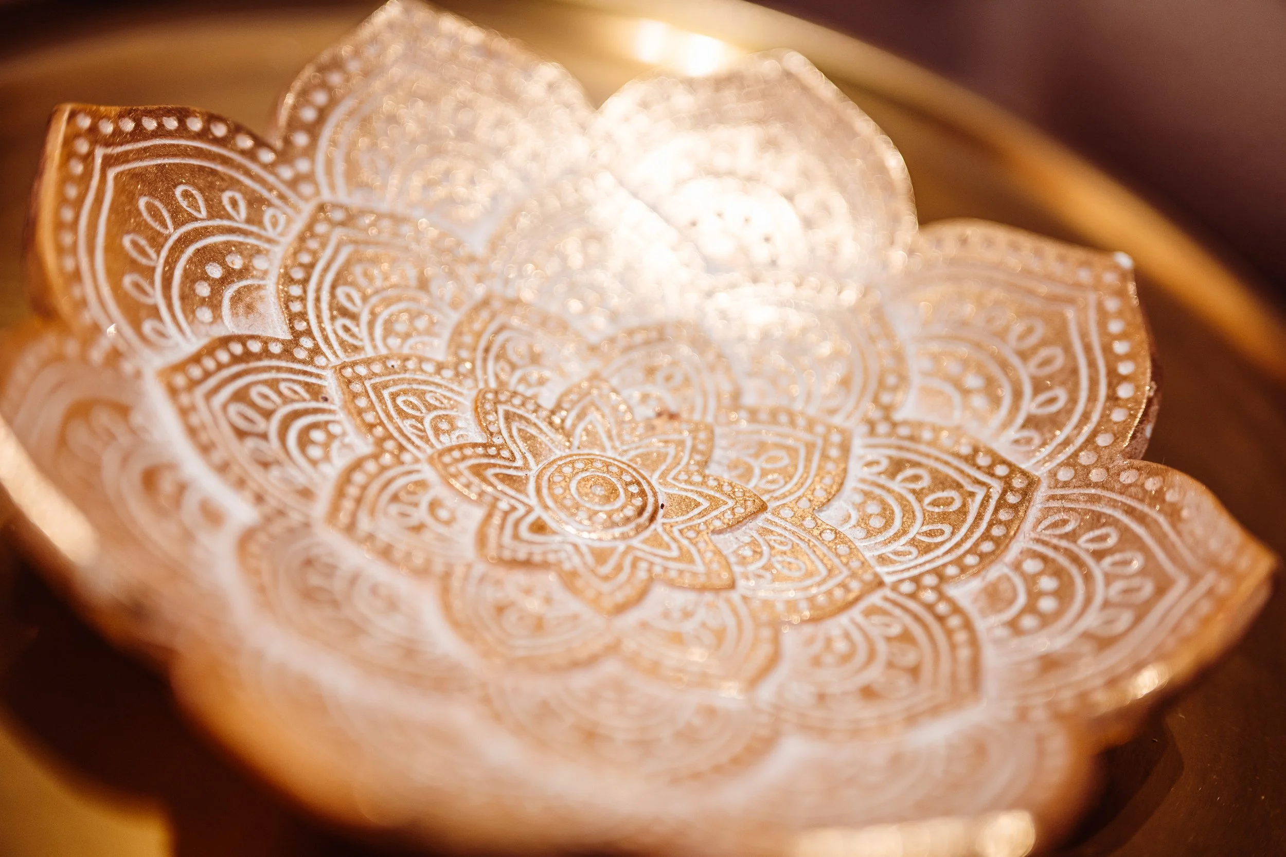 Goudkleurige decoratieve lamp met een mandala patroon en een zachte gloed.