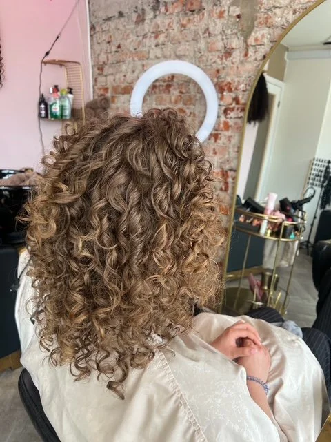 Kop van iemand met gekruld bruin haar in een kapselstudio.
