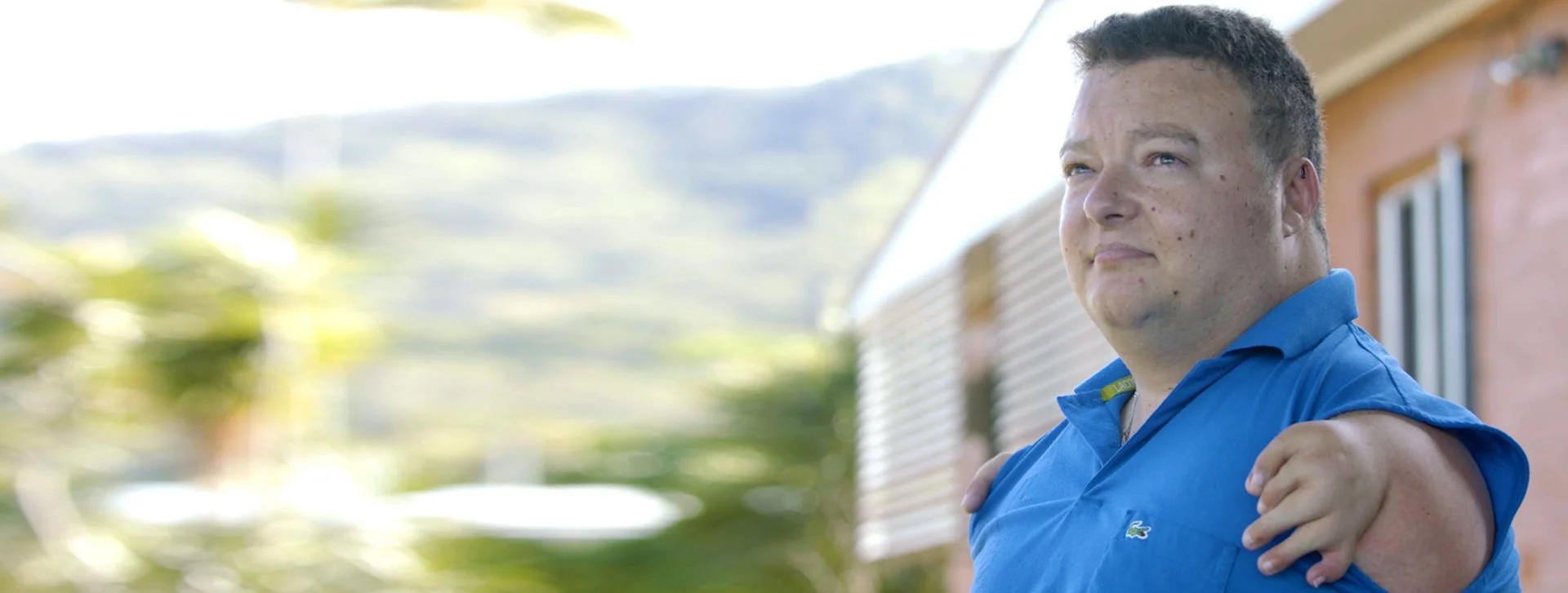 Allan Bunyan A young man in a blue polo shirt stands outside, looking into the distance with a determined expression 