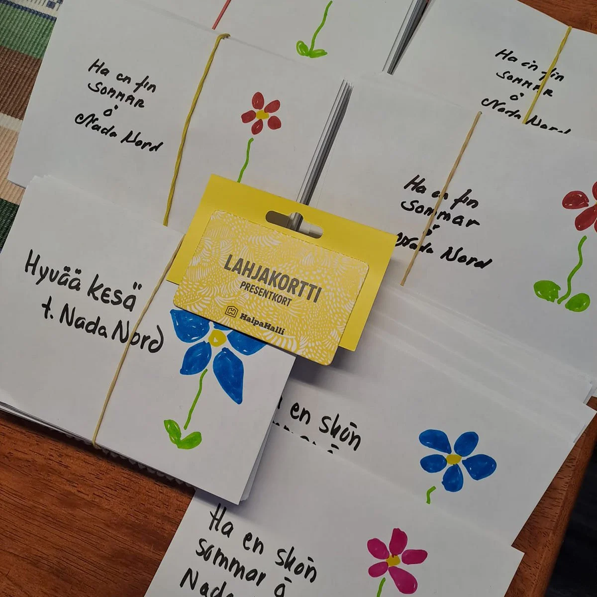 Presentkort från HalpaHalli och kuvert med målad blomma och sommarhälsning från Nada Nord