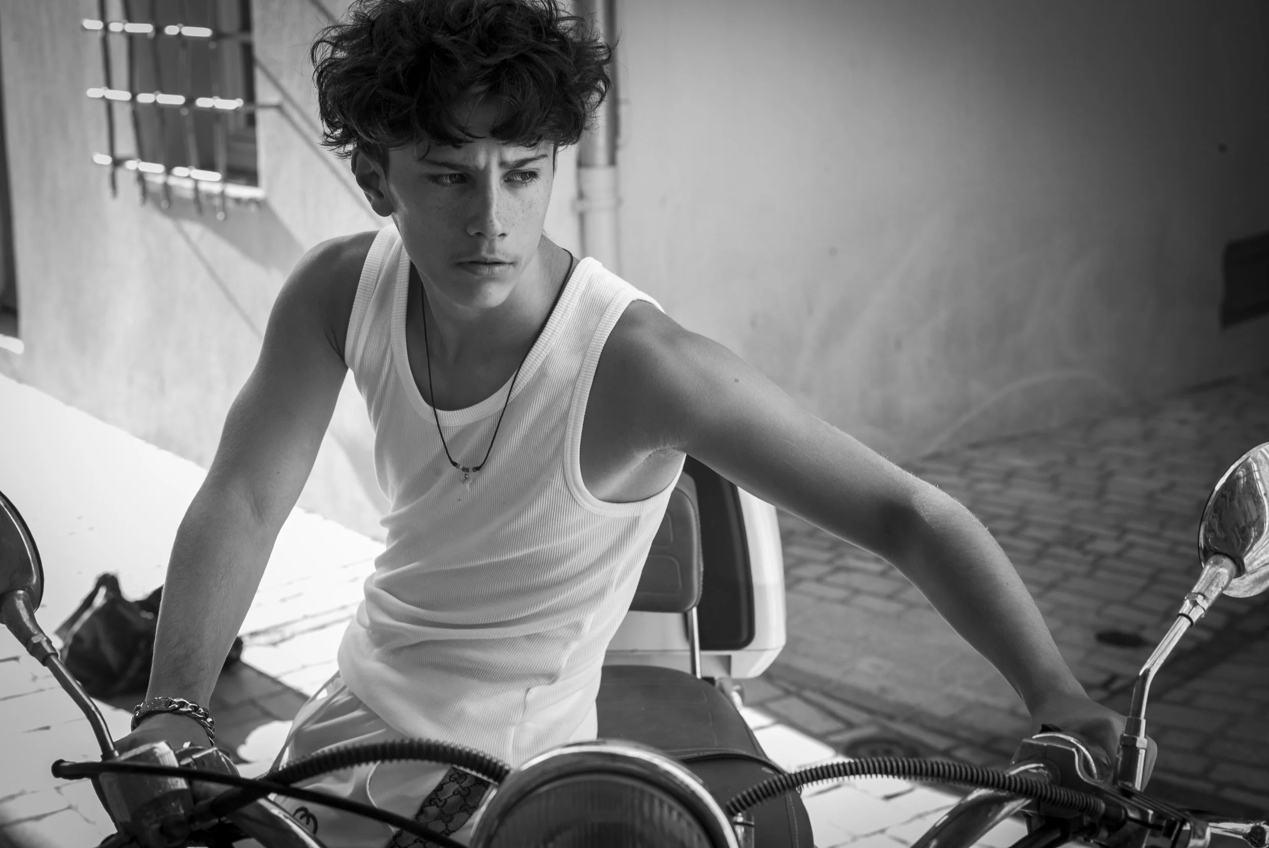 Black-and-white photograph of Sebastien Browning seated on a scooter, looking to the side.