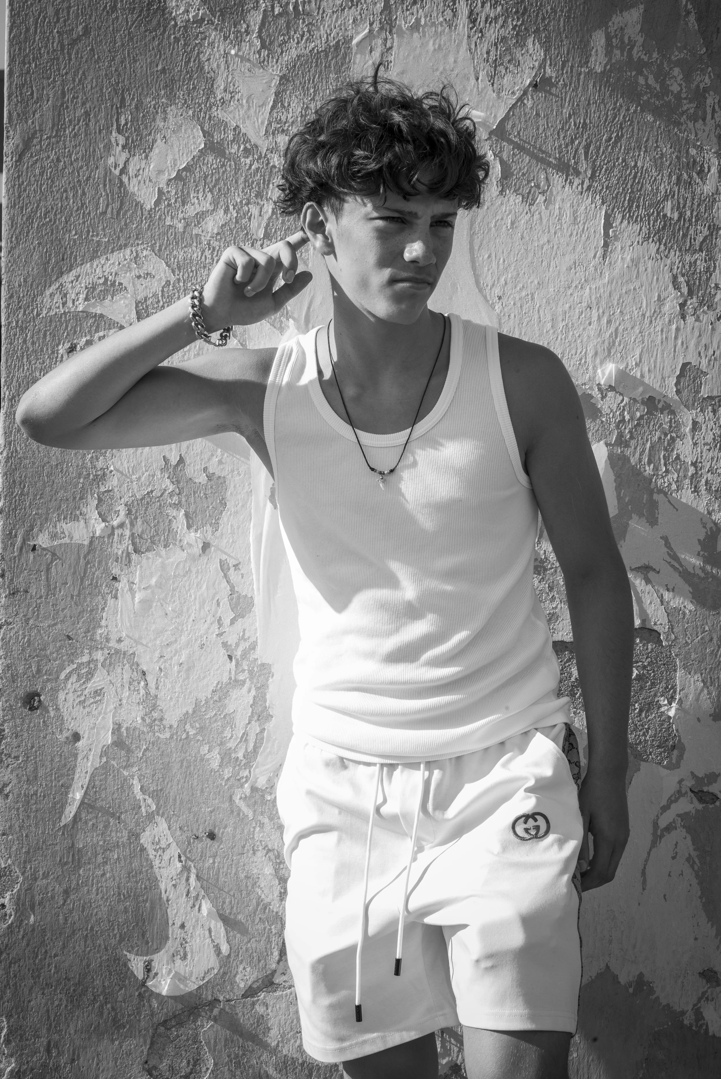 Black-and-white photograph of Sebastien Browning standing beside a textured wall in a white sleeveless top and shorts.